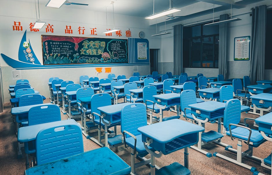 Spacious classroom with blue desks and vibrant decorated chalkboard, ready for students