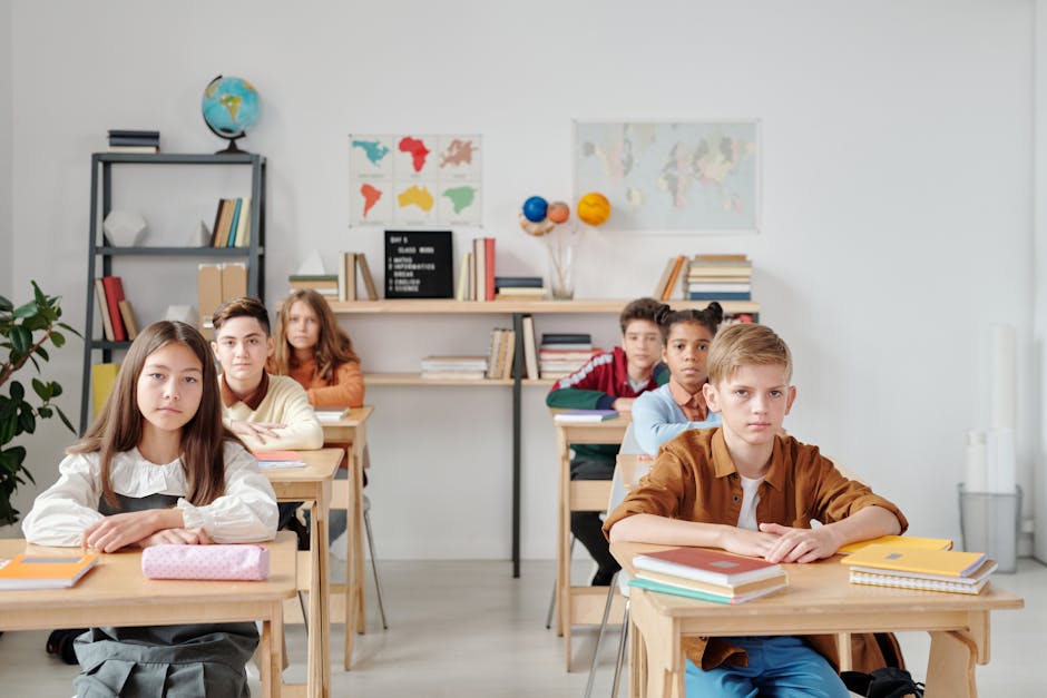 Students sit attentively in a modern classroom with books and maps, focused on learning