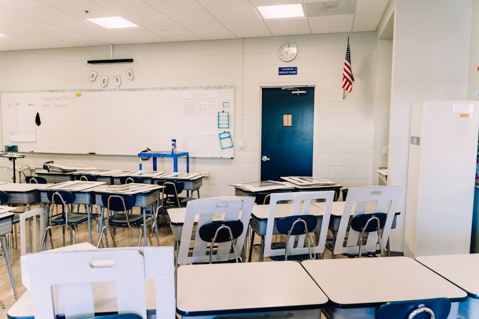 Bright empty classroom featuring desks, a whiteboard, and an American flag. Ideal learning environment